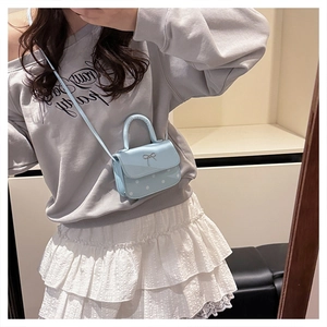 Detail of light blue mini handbag featuring white polka dots and silver bow decoration
