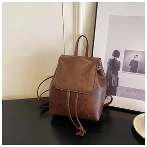 Detail of vintage brown faux leather backpack with flap closure and drawstring texture