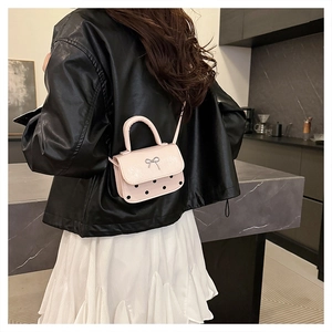 Pink mini square bag with metal bow detail and polka dots shown on model
