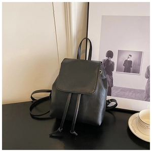 Detail of minimalist black faux leather backpack with drawstring closure and slim straps