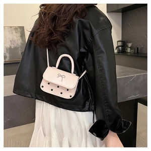 Pink mini crossbody bag with silver bow and black polka dots shown on model