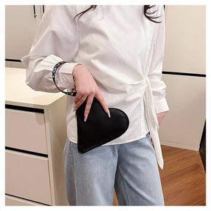 Detail of heart-shaped black leather handbag with colorful LOVE strap on a casual model