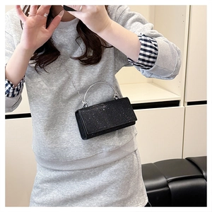 Detail van een zwarte glitter mini crossbodytas met zilveren handvat en metalen ketting