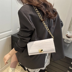 White crocodile pattern baguette bag with gold chain strap shown on model's shoulder