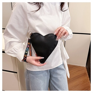 Detail of black heart-shaped handbag with Love print strap and lychee leather texture