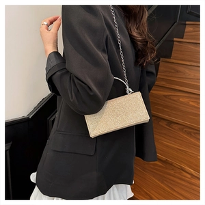 Detail van glitter champagne clutch met halfrond metalen handvat en zilveren ketting