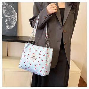 Detail of light blue cherry print tote bag with silver metal chain and fabric strap