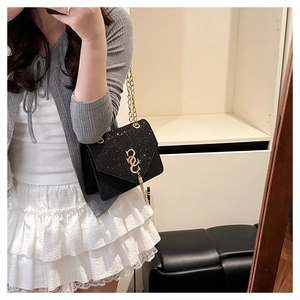 Close-up of black glitter crossbody bag featuring golden logo and fringe tassel details