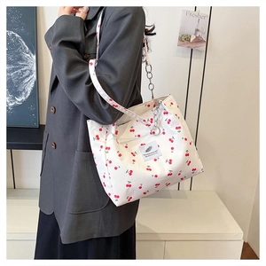 Detail of white nylon underarm bag with red cherry print and silver chain shoulder strap