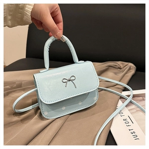 Detail of light blue polka dot handbag with a silver metal bow buckle and top handle
