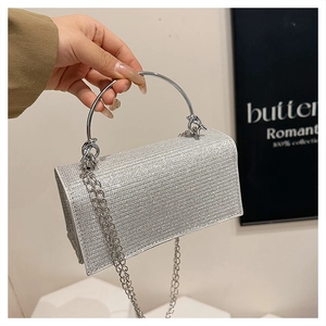 Detail van zilveren avondtas met strass-steentjes, ronde metalen handgreep en dunne ketting