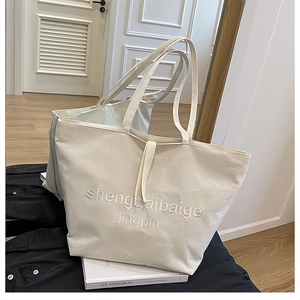 Detailed macro of off-white canvas tote bag featuring premium 3D textured embroidery