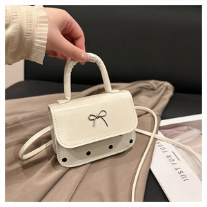 Detail of cream mini handbag with silver metallic bow and black polka dot pattern