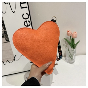 Macro shot of orange heart-shaped clutch with lychee leather texture and LOVE wrist strap