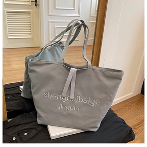 Detail view of the embroidered gray-blue canvas tote bag with thick woven handles