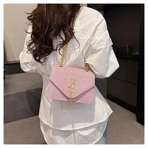 Detail of pink sequin crossbody bag with gold SS logo and tassel on female model