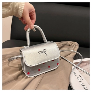 Detail of silver mini crossbody bag with red polka dots and metal bow charm
