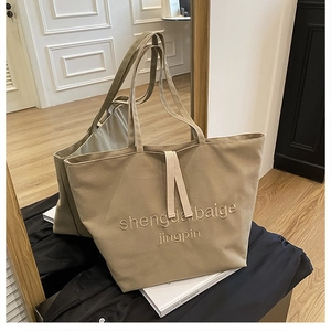 Detail of khaki canvas tote bag featuring premium 3D letter embroidery and double handles