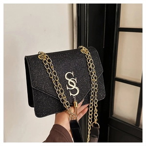 Close-up of black glitter crossbody bag with gold S-logo and metal chain strap