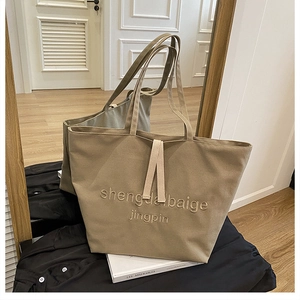 Detail of khaki canvas tote bag featuring embroidered lettering and durable fabric texture