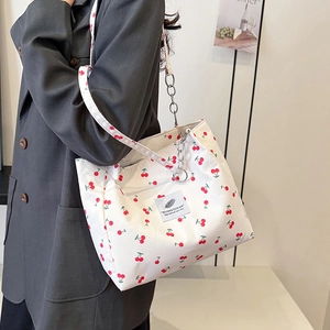 White canvas tote bag with red cherry print featuring dual shoulder straps and chain