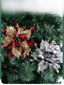 Detail of red and black plaid Christmas flowers with gold glitter on a green pine tree