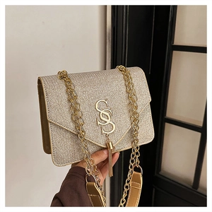 Detail of glitter gold crossbody bag featuring gold SS metal logo and elegant tassel