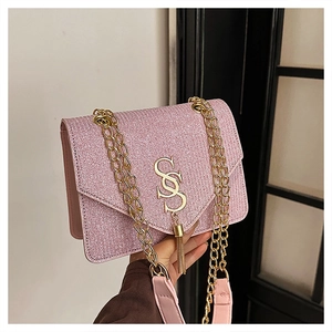 Detail of pink sequin crossbody bag with gold S-shaped logo and metallic tassel