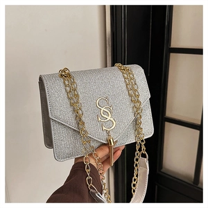Detail of silver sequin bag featuring gold S-logo hardware and metallic tassels