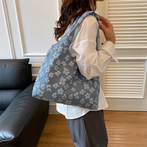 Borsa tote blu con texture jacquard floreale 3D indossata da una modella in un interno