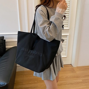 Large black canvas tote bag with textured embroidery for casual commuting and daily use