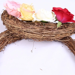 Detail of handmade crescent rattan wreath with colorful silk roses and green leaves