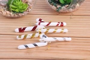 Close-up of red, gold and silver striped candy cane ornaments with hanging strings