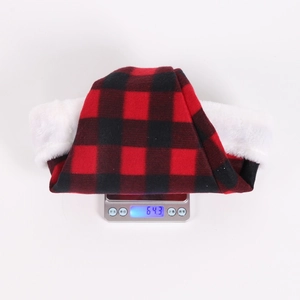 Detailed view of lightweight red and black plaid flannel Christmas hat on a scale showing 64g