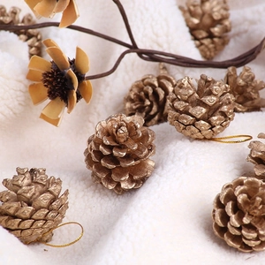 Close-up of golden pine cones with strings on white fur for Christmas tree decoration