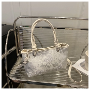 Detail of white lace tote bag featuring delicate butterfly embroidery and adjustable strap