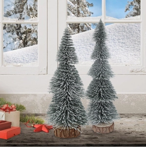 Close-up of two mini snowy Christmas trees with natural wood bases on a winter tabletop
