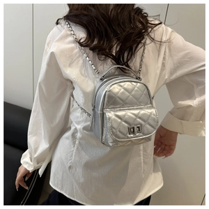 Detailed view of silver quilted mini backpack with chain straps on model back