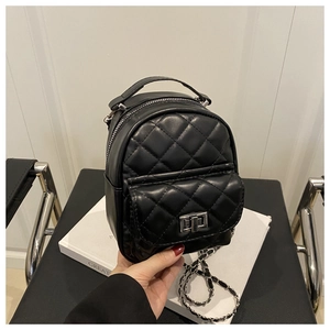 Detail of black quilted mini backpack featuring silver twist-lock and leather chain straps