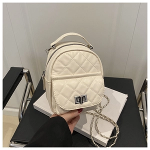 Close-up of quilted cream mini backpack with silver chain strap and metal rotary buckle
