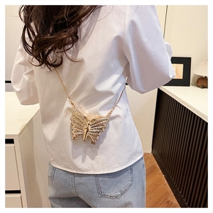 Detail of a golden butterfly crossbody bag with rhinestones worn by a model
