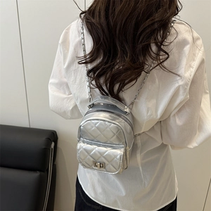 Silver quilted mini backpack with metallic finish and chain straps on model back