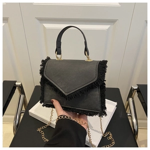Close-up of black fringe texture and golden chain on stylish denim top handle bag