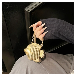 Detail of a golden fish-shaped evening clutch with textured scales and chain strap