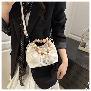 Close-up of white drawstring bucket bag with decorative faux-agate beaded handle