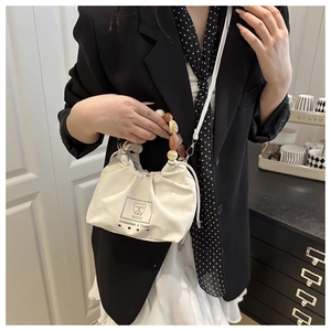 Detail of white canvas bucket bag with colorful beaded handle and drawstring closure