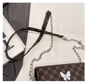 Detail of vintage crossbody bag featuring old-flower pattern and butterfly buckle