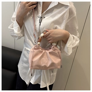 Detailed view of pink drawstring bucket bag with pearl handle and adjustable strap