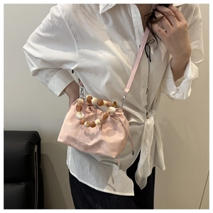 Pink drawstring bucket bag with bear motif and amber beaded handle worn cross-body