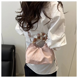 Pink canvas bucket bag with resin bead handle and shoulder strap shown on model